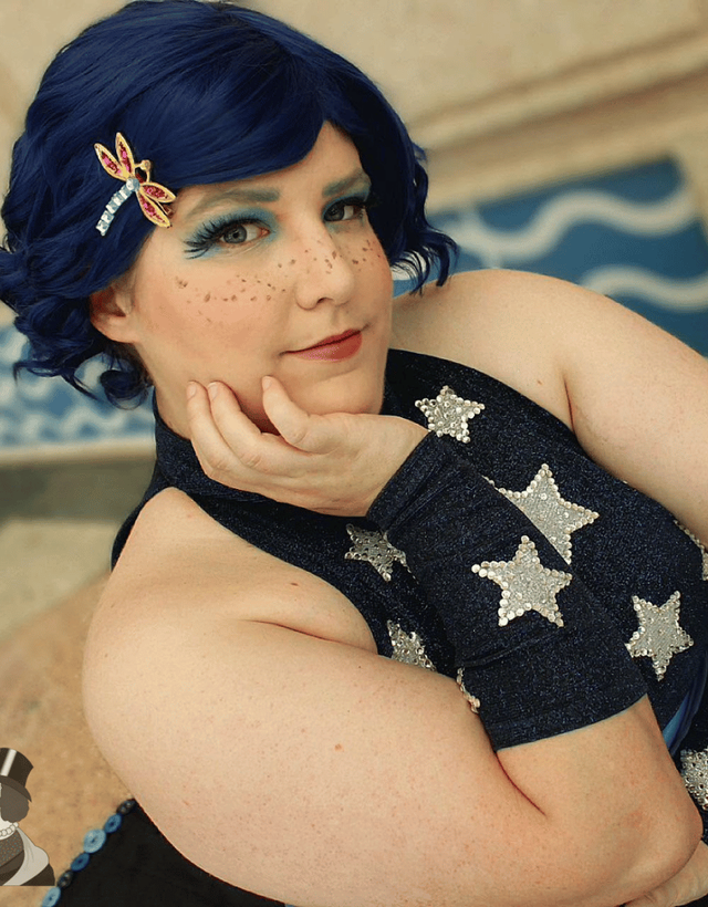 Emma in cosplay, blue halter top with silver stars, and a blue wig