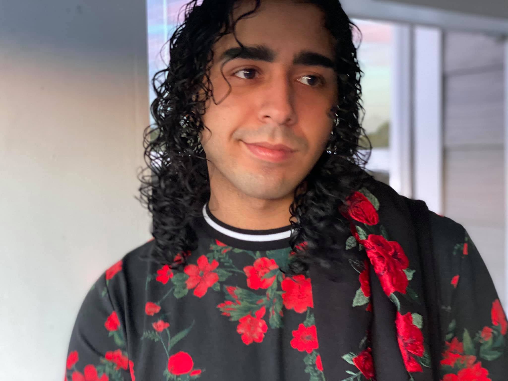 hispanic person in black shirt with a red rose print